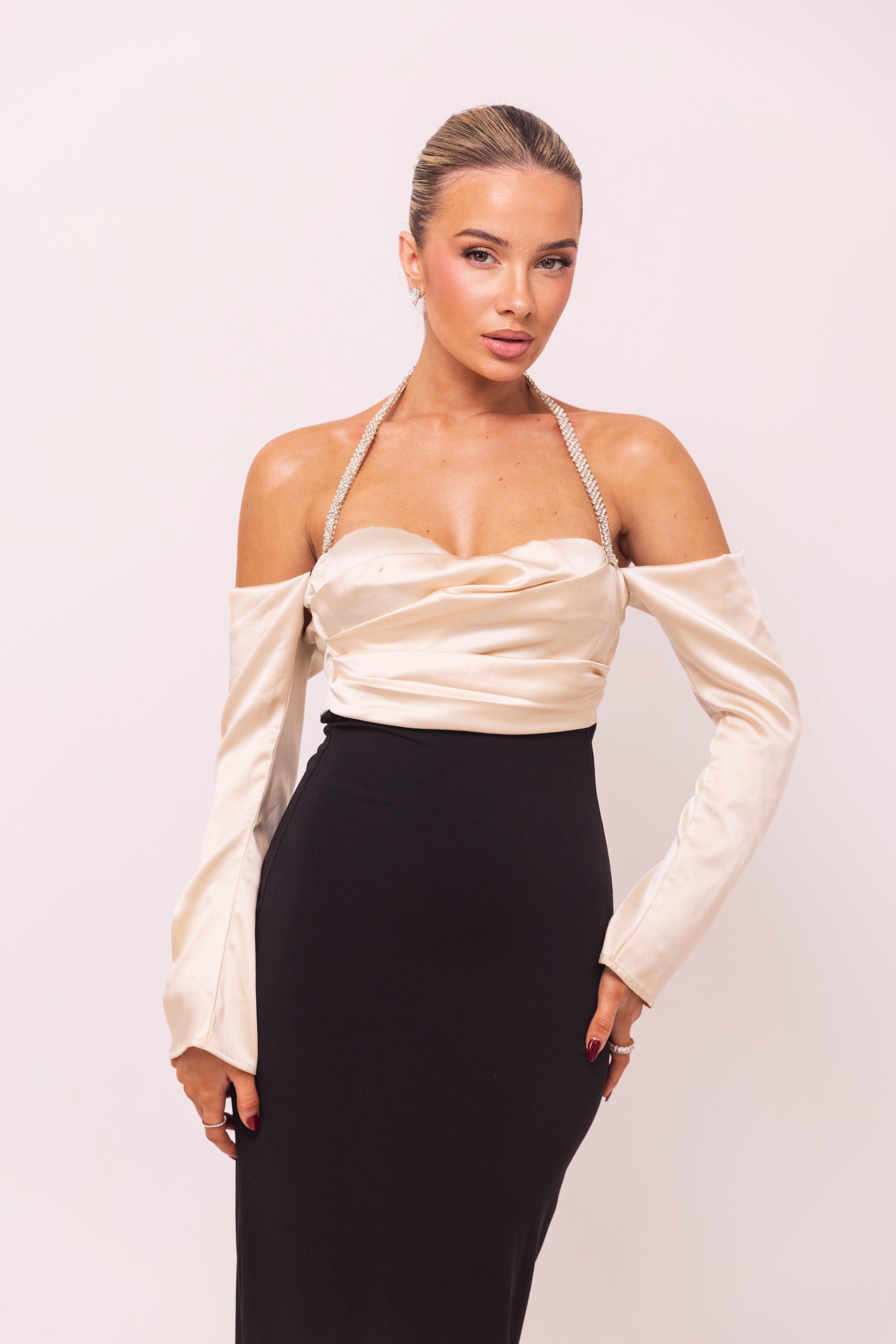 two-tone dress featuring a satin off-shoulder ivory top with embellished straps and a fitted black skirt for an elegant look.