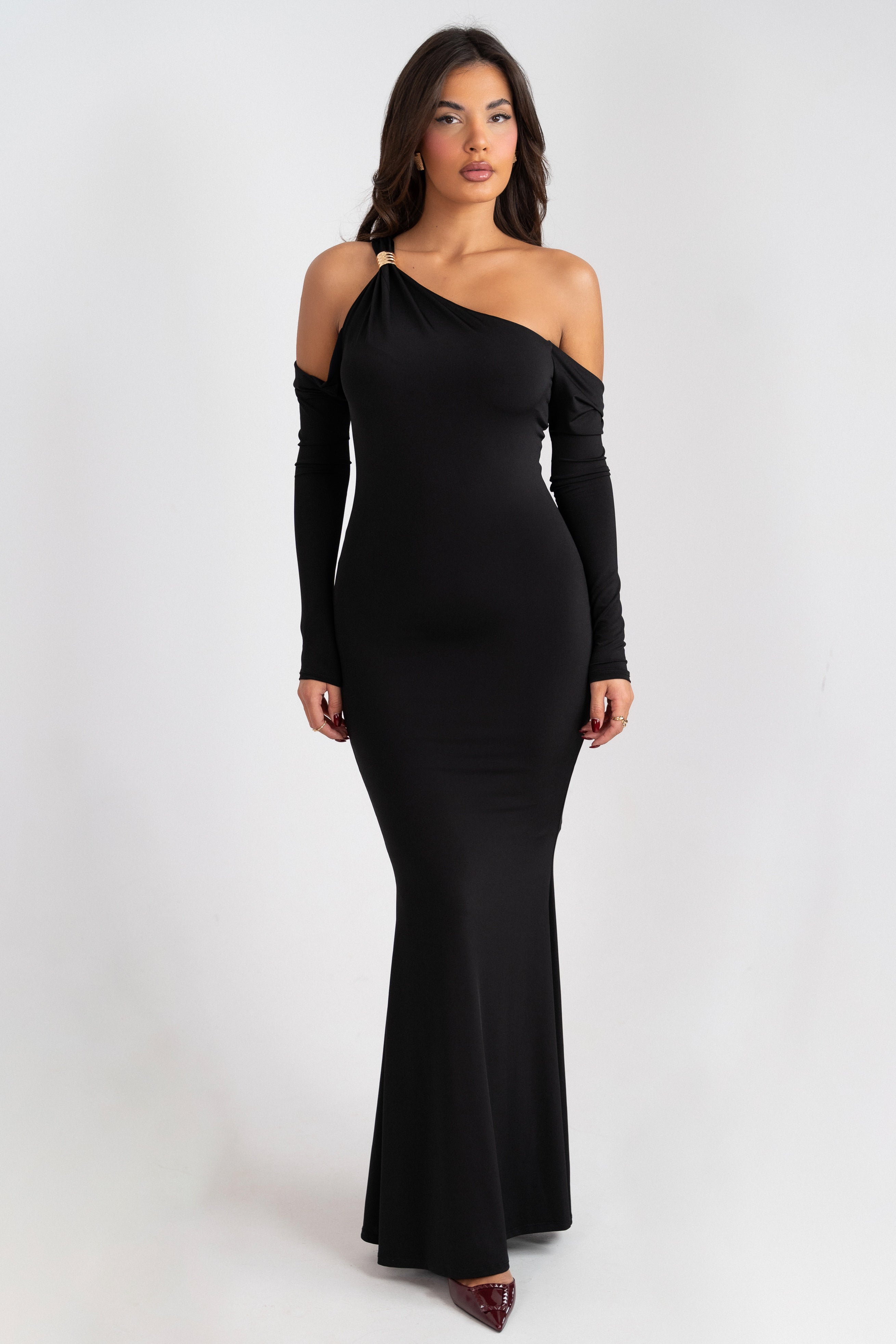 Black dress with an asymmetrical neckline and a gold accent on the strap