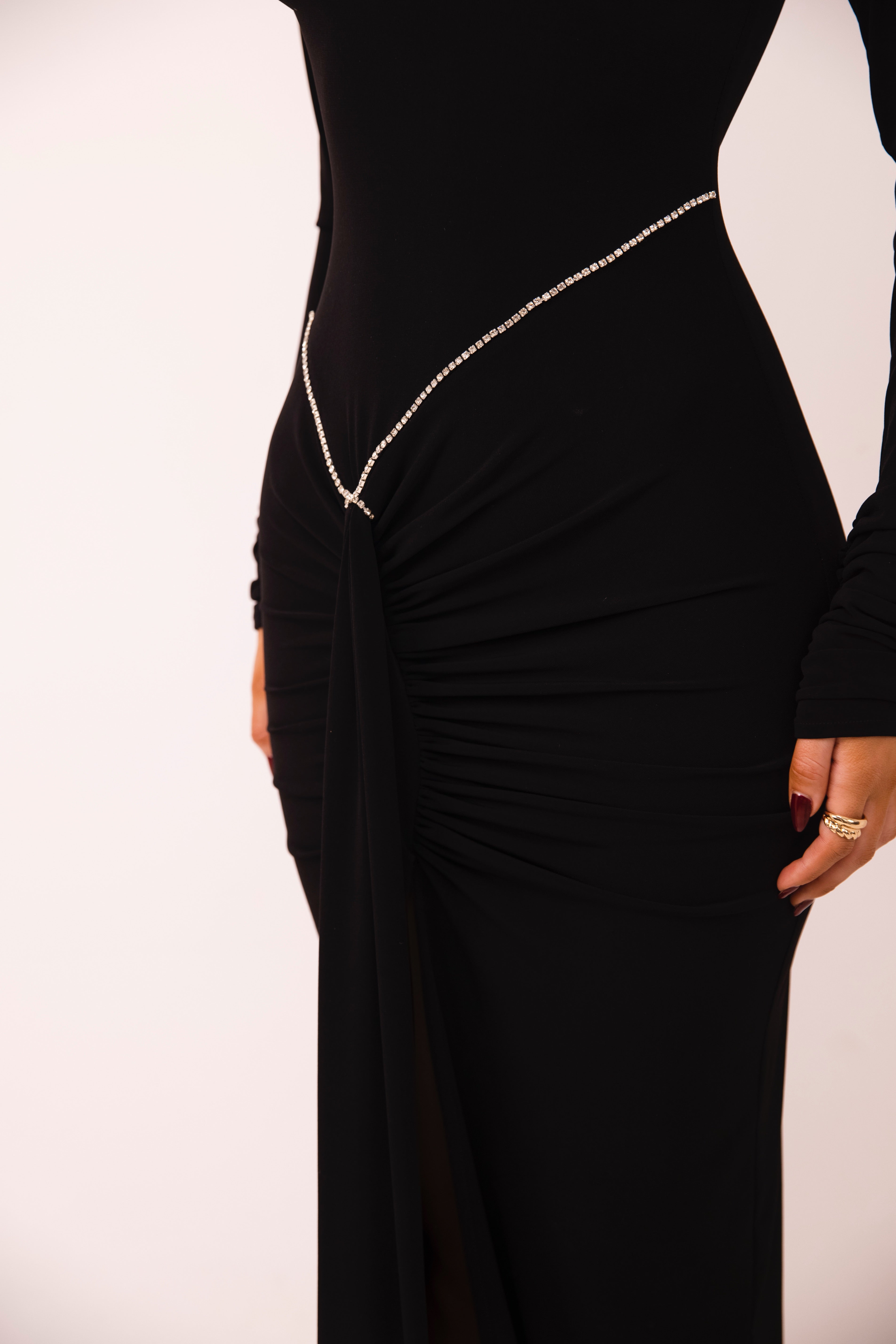 Stylish black gown featuring long sleeves and a glittering chain accent for added elegance