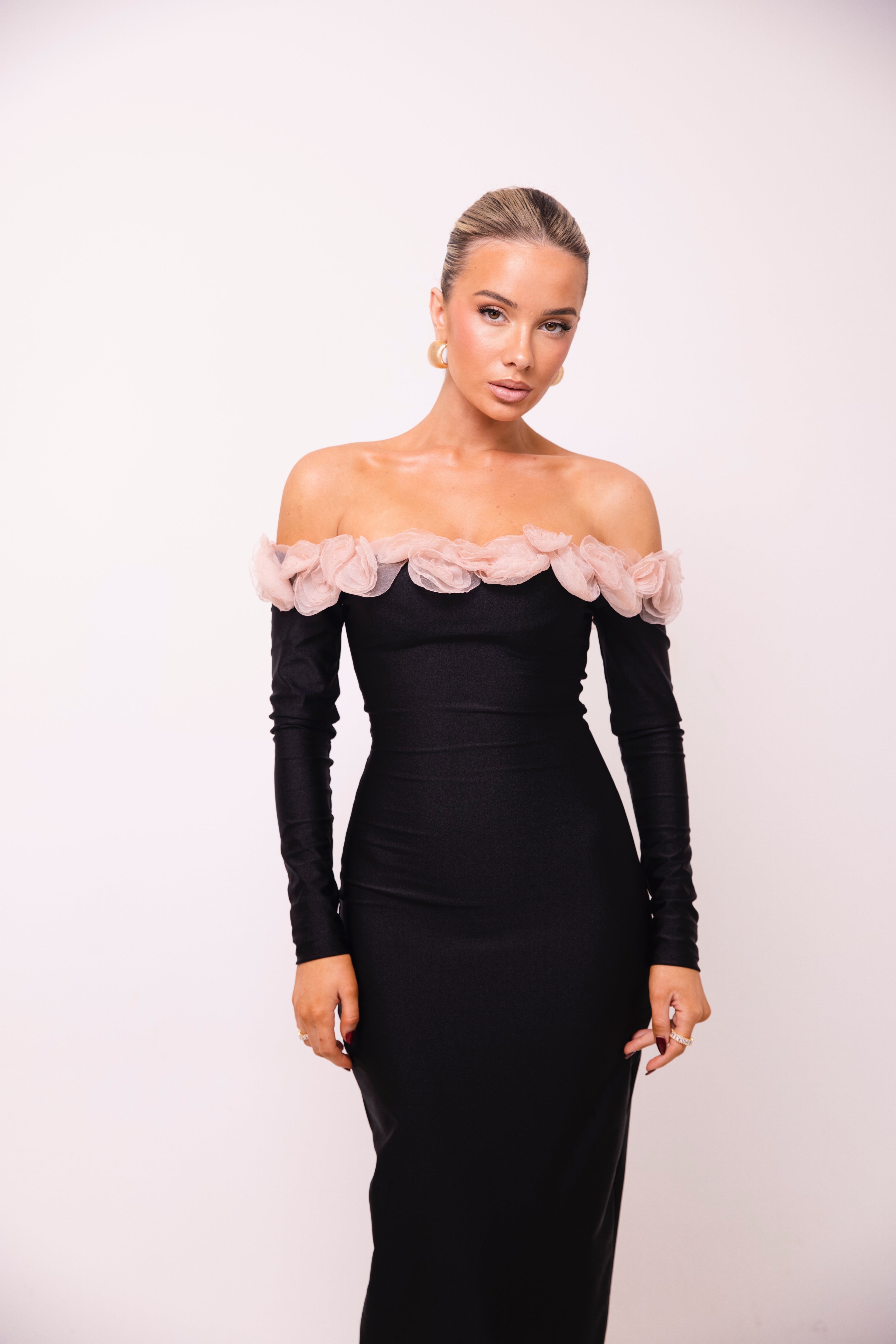 Sophisticated black dress with an off-shoulder design and light pink flower embellishments